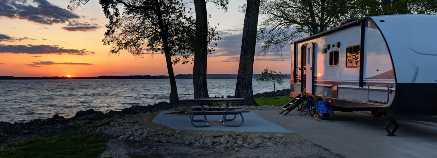 RV sitting next to lake.