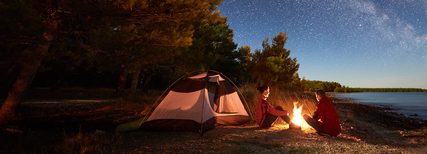 Couple camping on  starry night next to fire