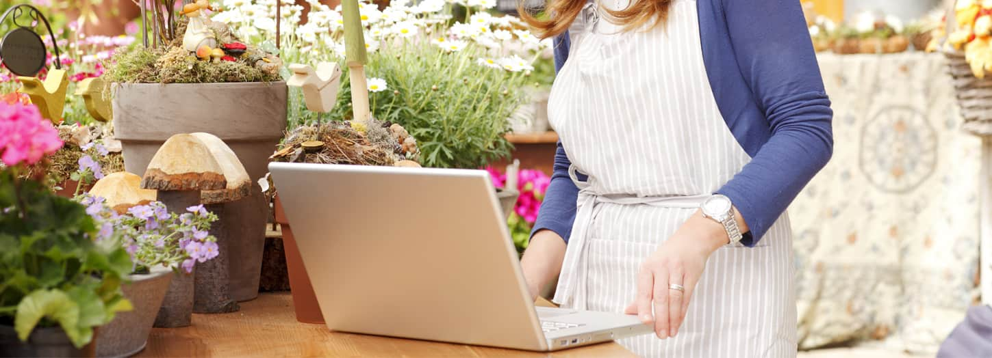 Woman flower shop owner using laptop.