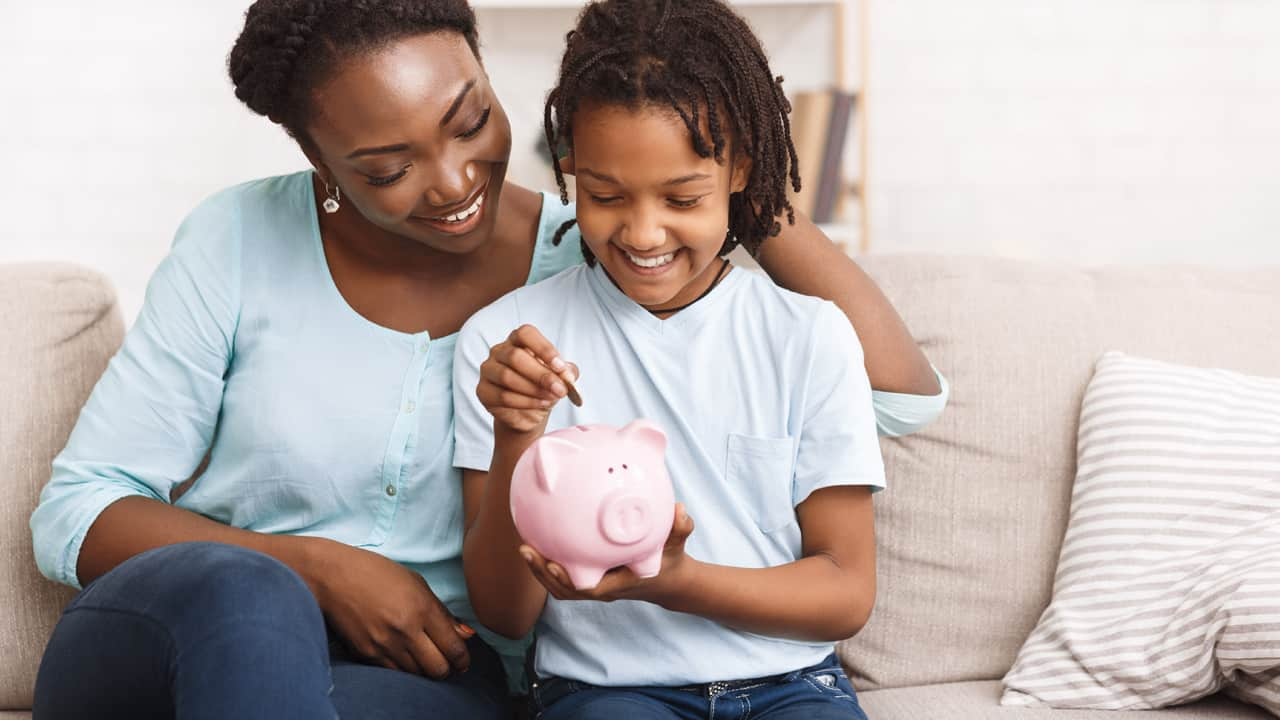 Young mom with daughter looking a piggy bank